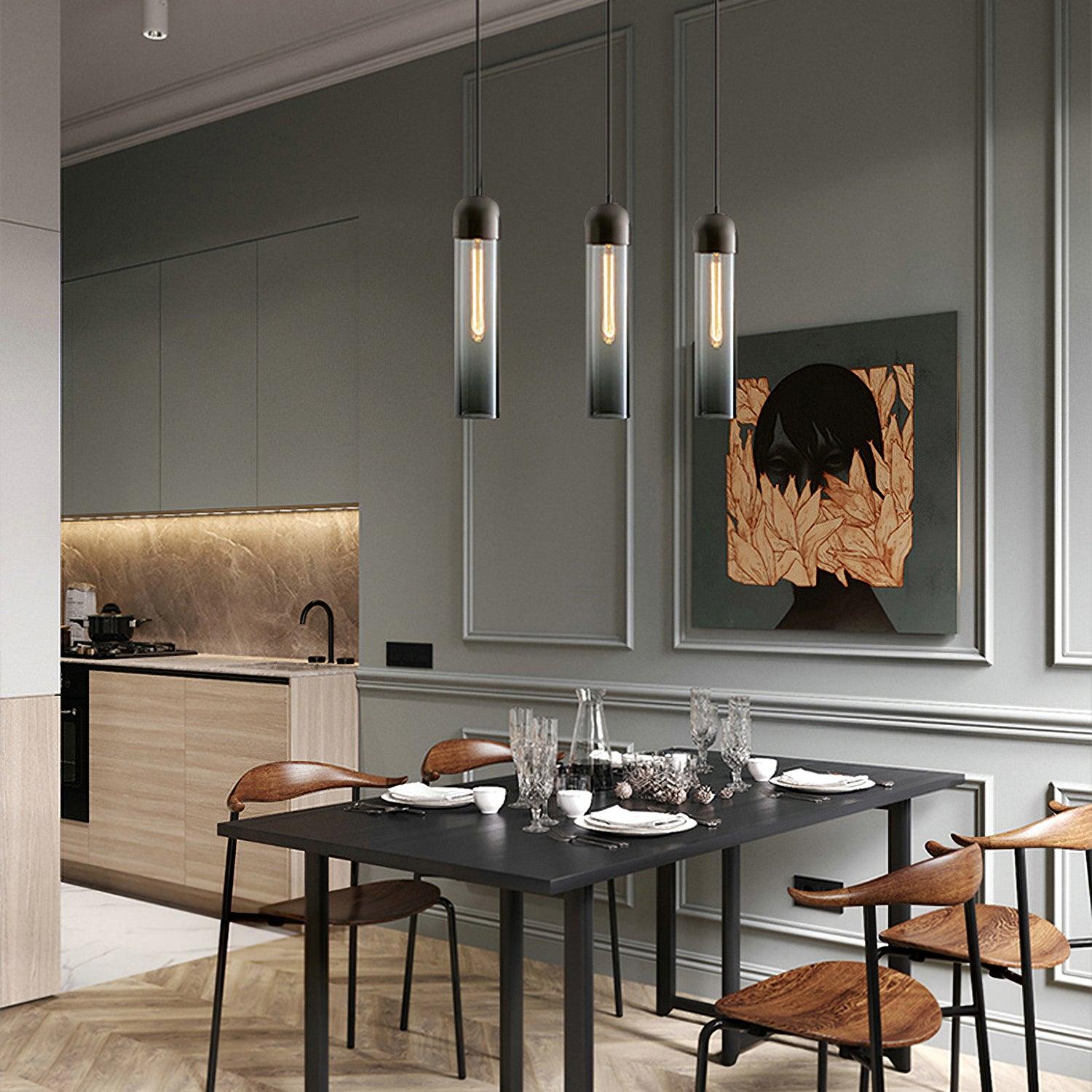 Three smoky glass cylinder pendants above a black dining table near kitchen cabinets