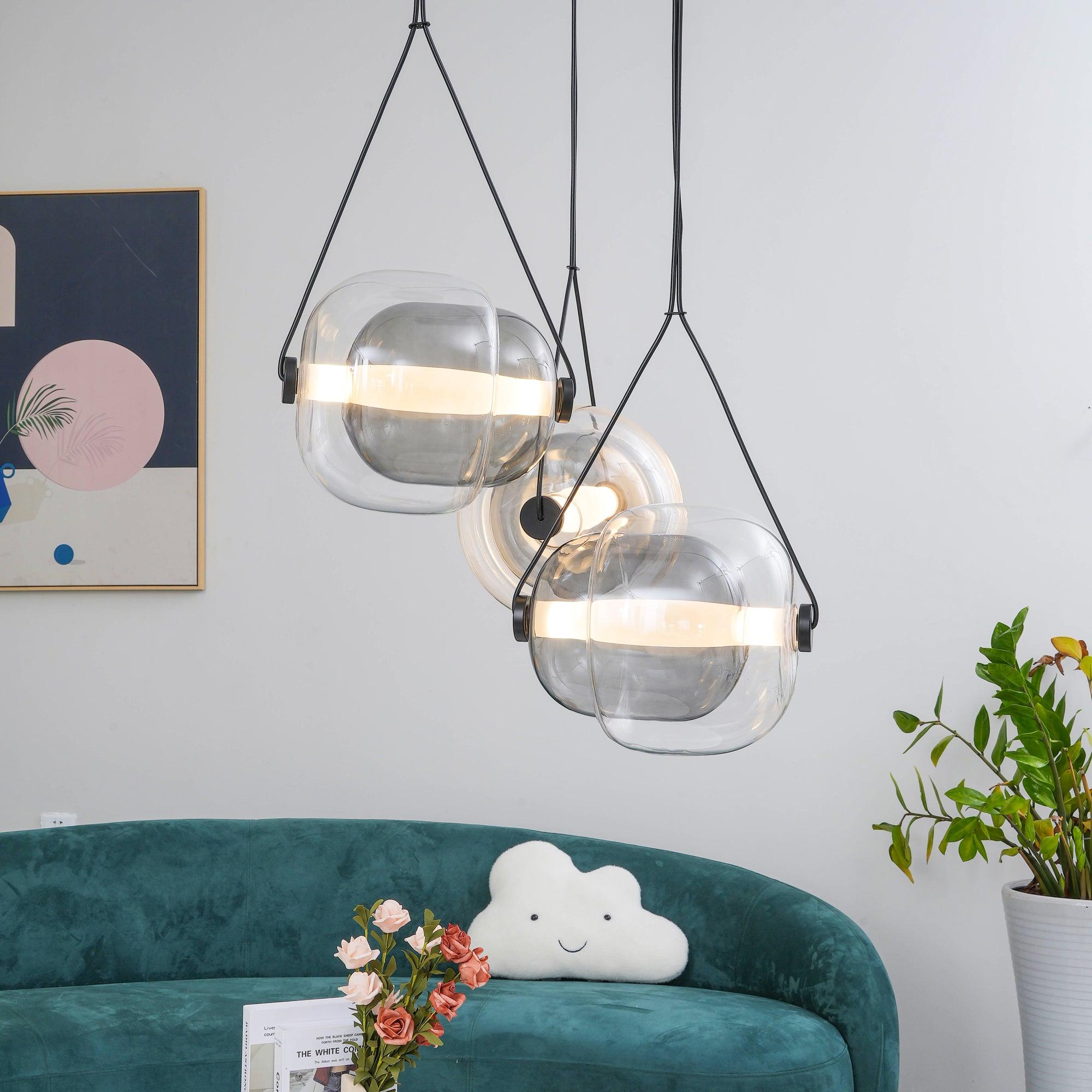 Two clear layered-glass pendants above a green sofa