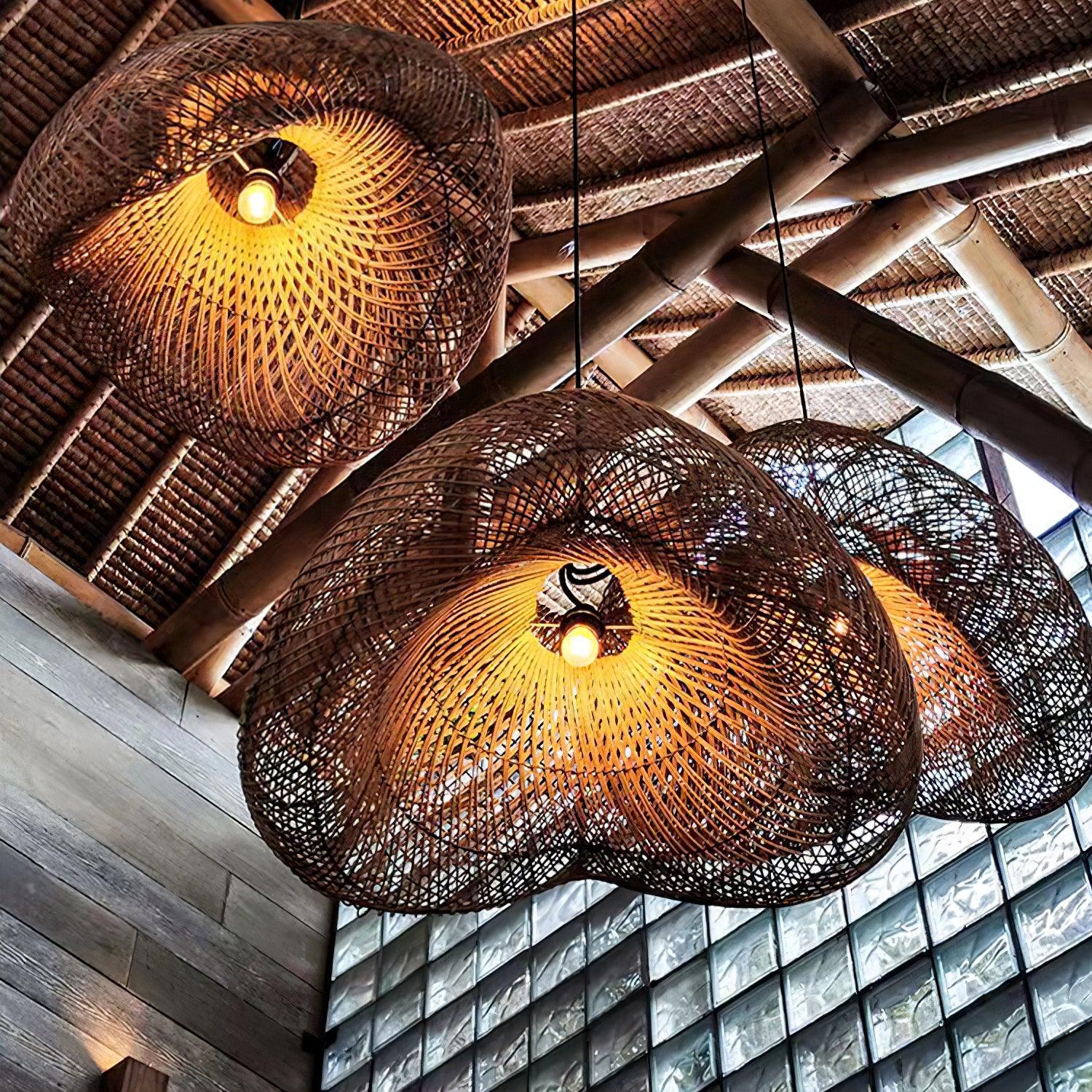 Underside view of three open woven shades with illuminated bulbs beneath beams beside a glass-block wall