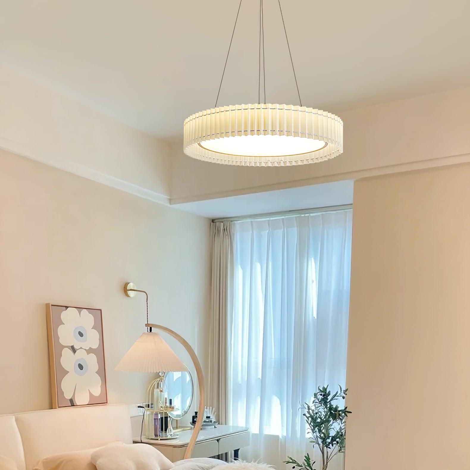 Pleated pendant in a bedroom with a round mirror, dressing desk, curved floor lamp and flower artwork
