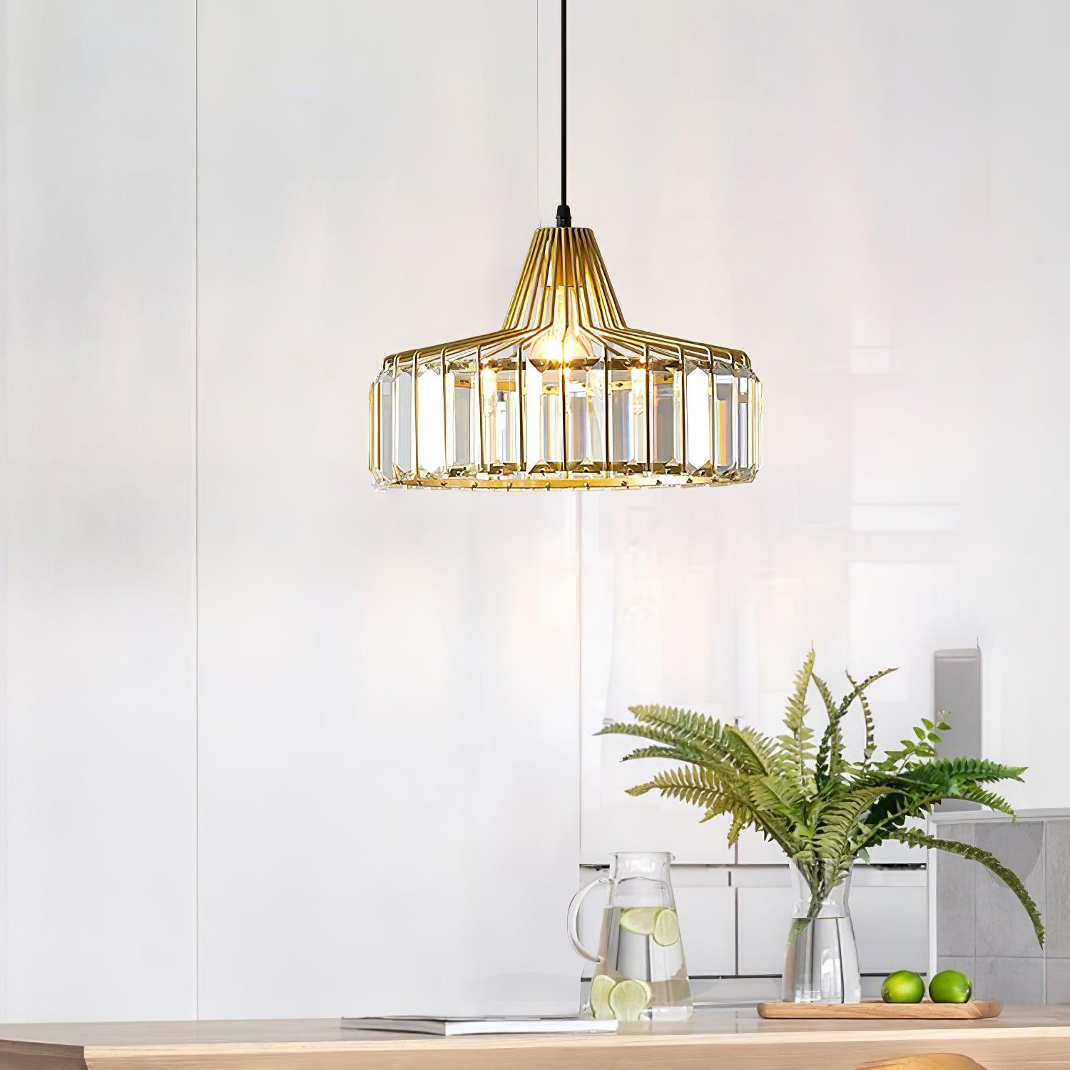 Gold-coloured crystal-glass pendant above a light wooden table with plants and fruit