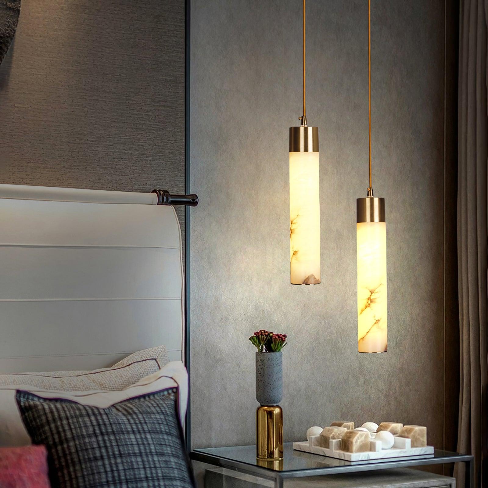 Two glowing stone tube pendants beside a sofa