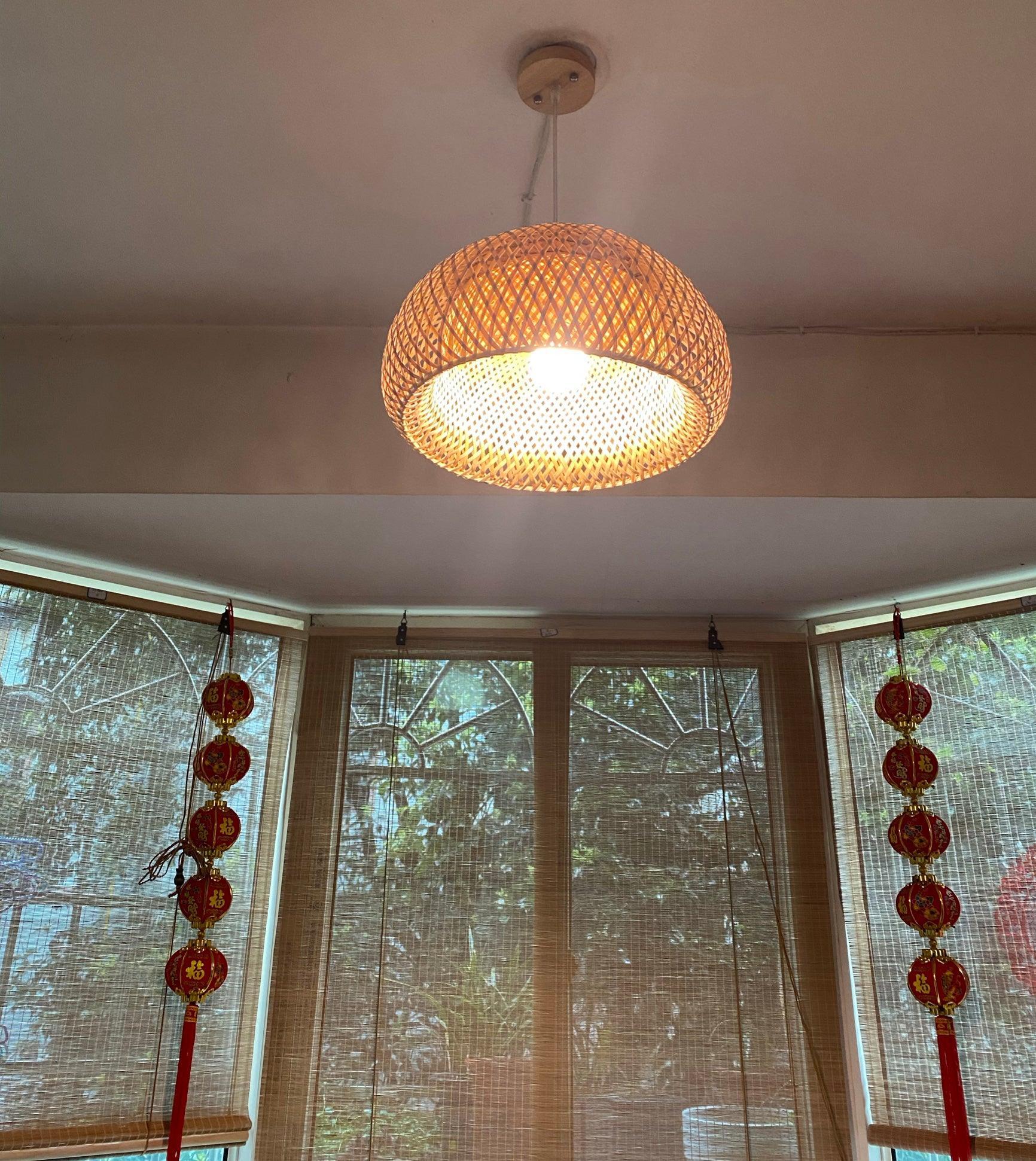 Lit bamboo dome with pale cord and tan canopy above a windowed room with woven blinds and red hanging ornaments