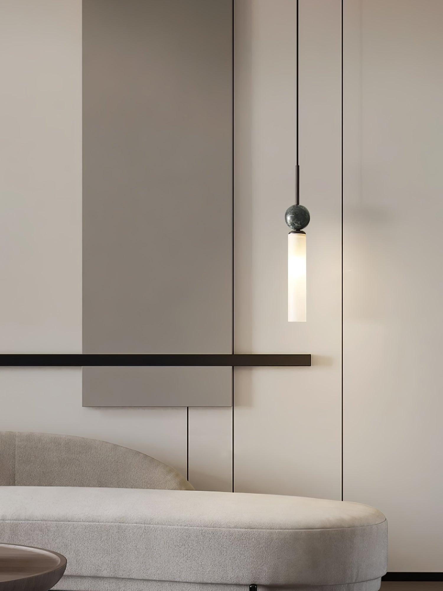 Single black-stem marble-sphere pendant over curved pale sofa, with paneled wall and round wood table partly visible