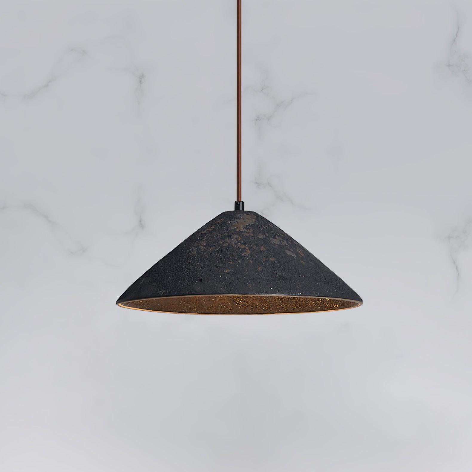 Close view of a black ceramic cone with brown distressed patches and brown suspension against a pale veined background