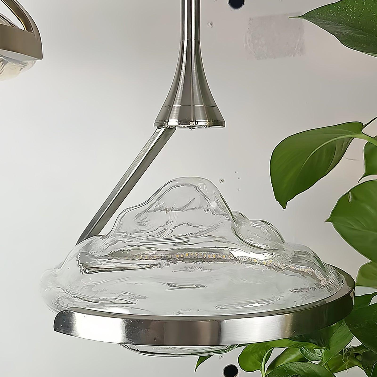 Chrome-looking flared head and angled support above rippled glass, with green leaves at the right