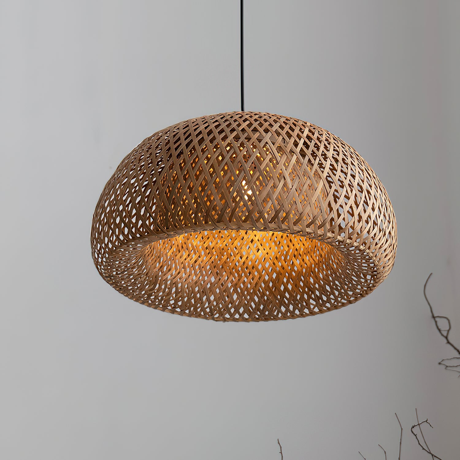 Angled close-up of glowing bamboo dome against gray background, showing open circular underside and crossed strips