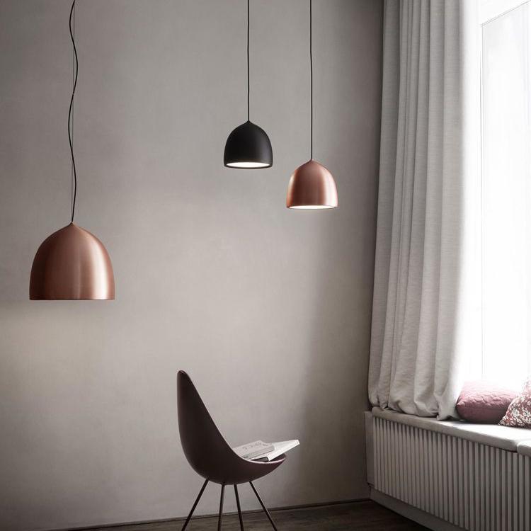 Copper and black bell pendants beside a chair