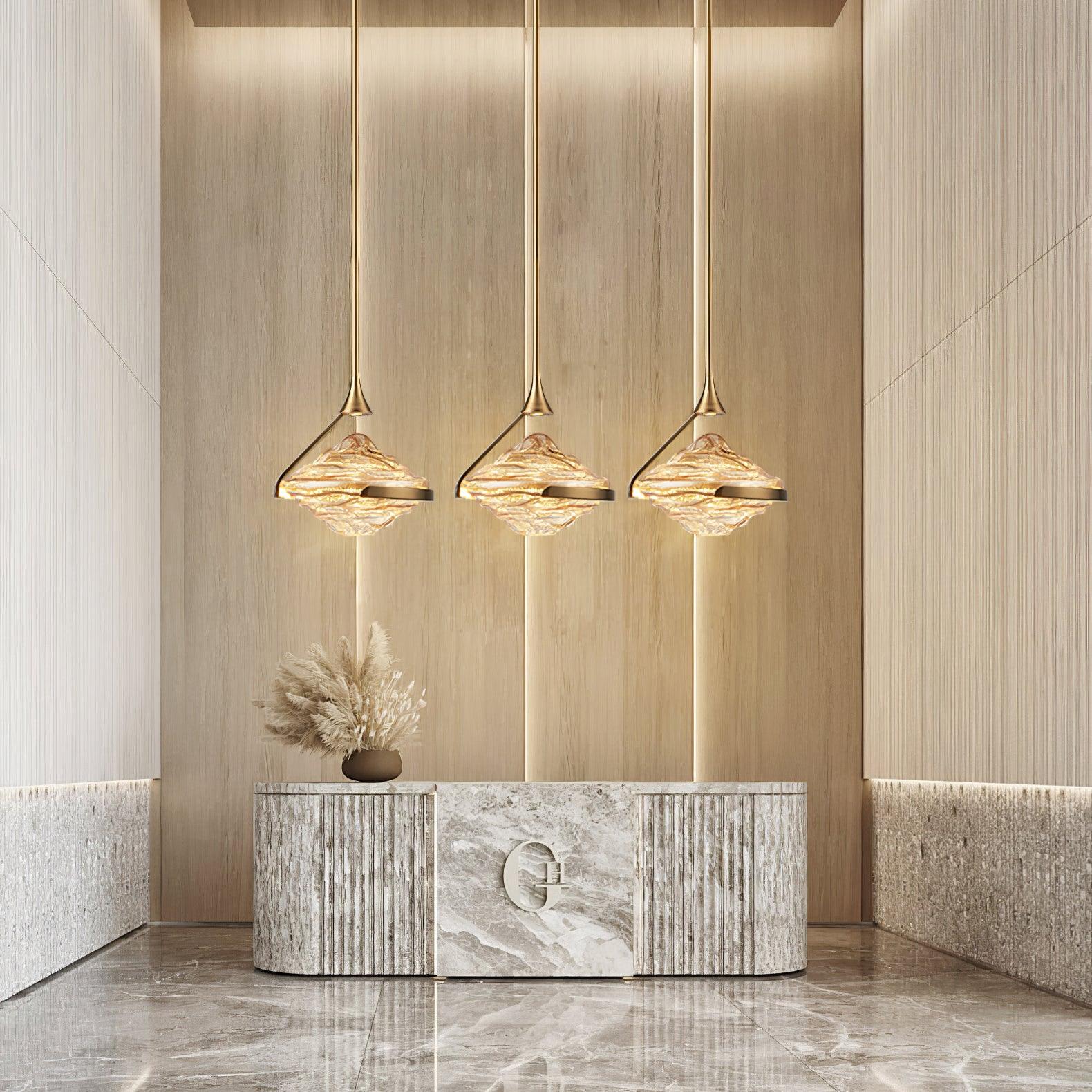 Three gold-toned rippled-glass pendants above a curved stone-pattern console with dried stems and timber wall panels