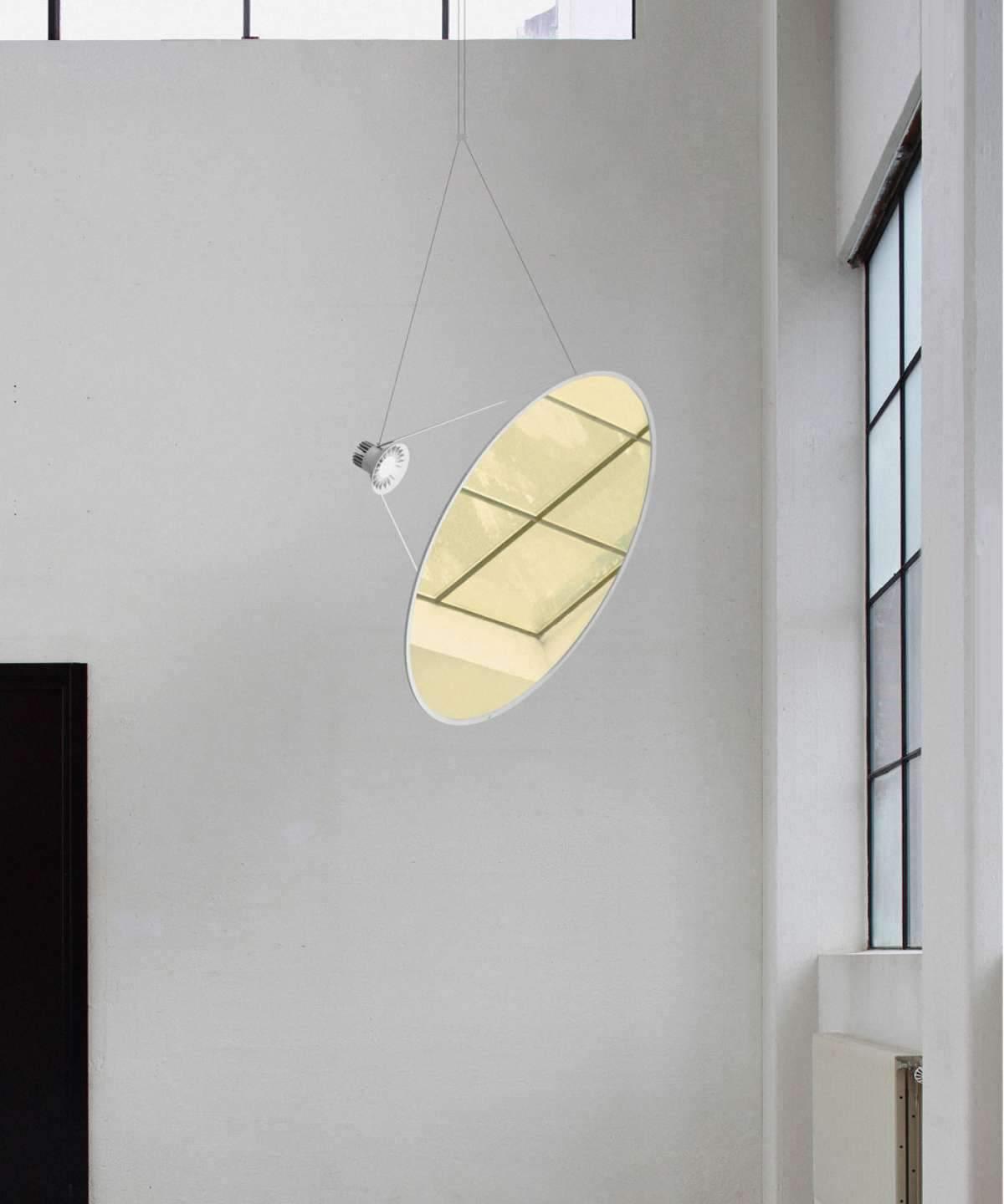 Reflective gold-toned disc suspended beside a tall window