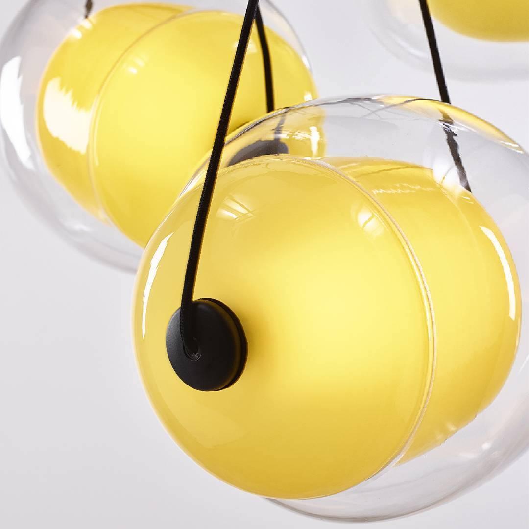Yellow inner glass inside a clear Capsula shade, with part of another yellow pendant behind it
