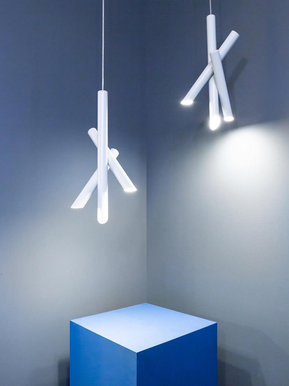 Two white Tubes pendants casting light on a blue wall above a blue cabinet
