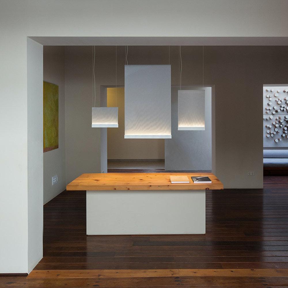 Three rectangular fabric pendants above a wood-topped white cabinet