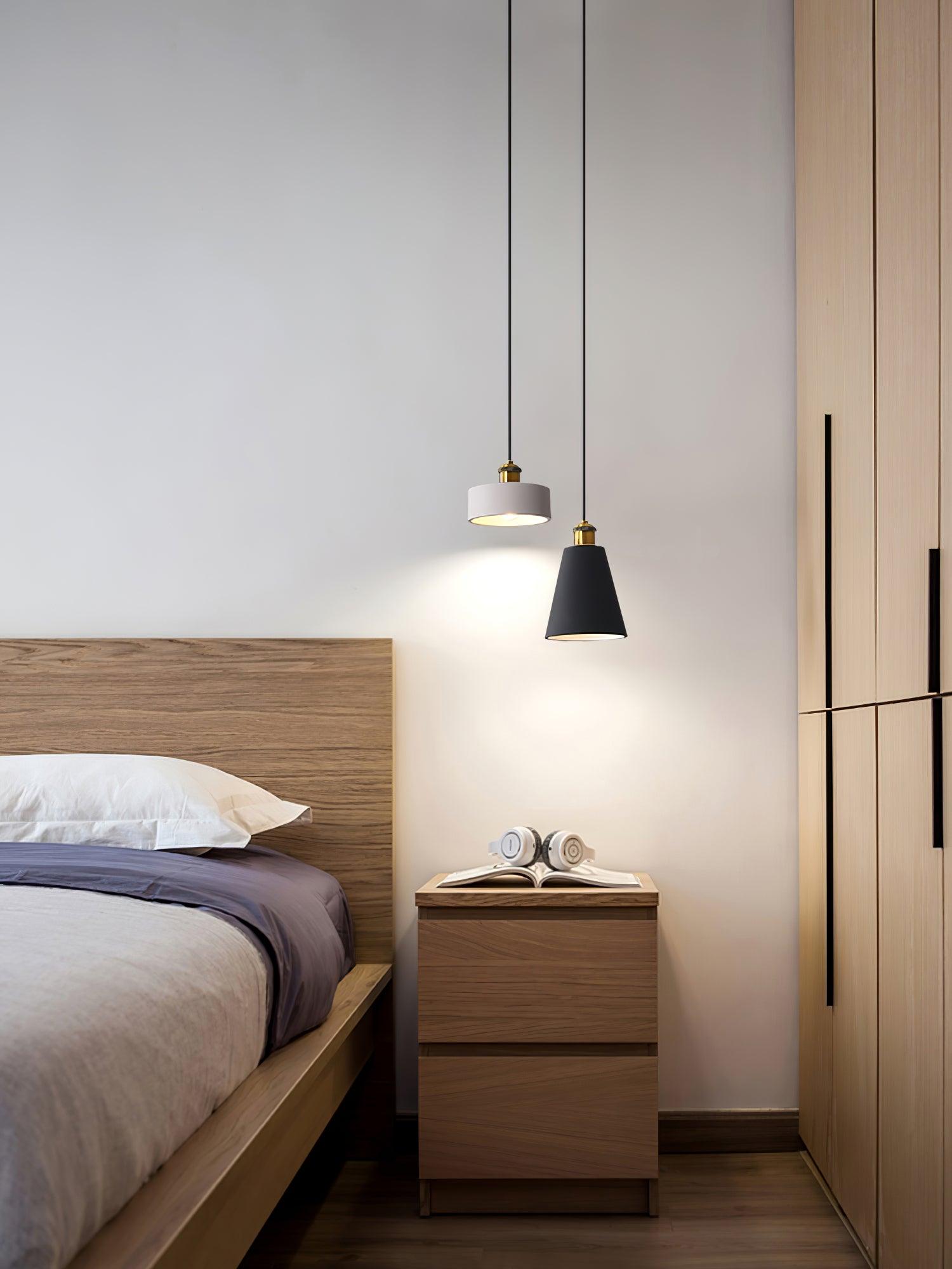 Three geometric pendants beside a bed and wooden bedside cabinet