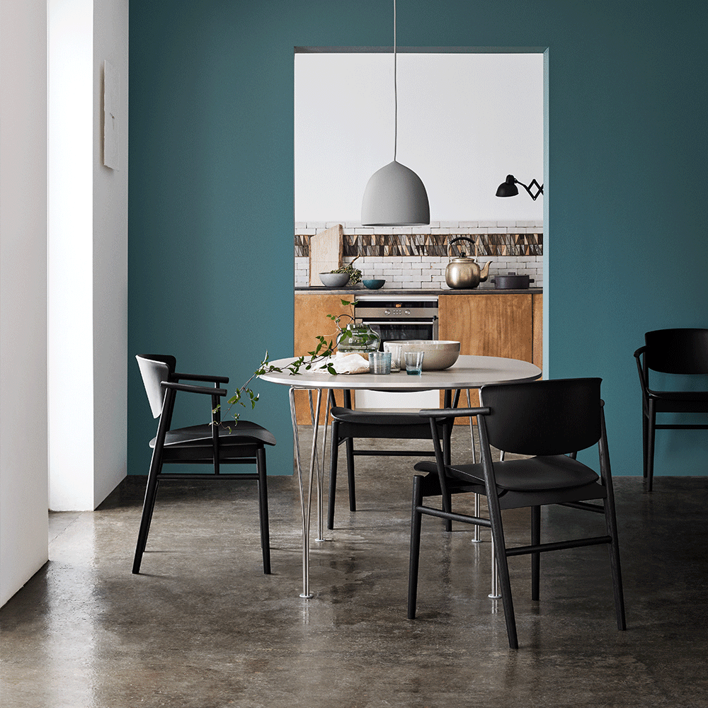 White bell pendant above a table in a teal dining room