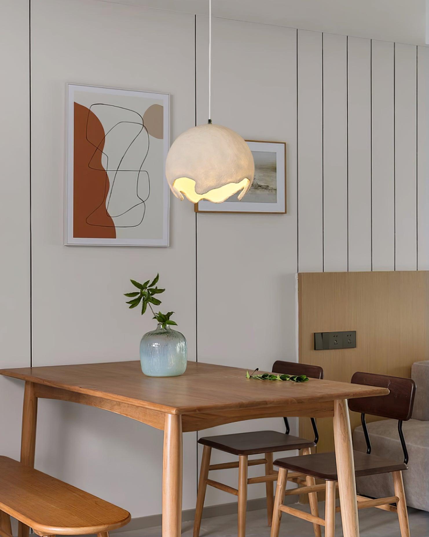 Beige globe light above a wooden table and artwork
