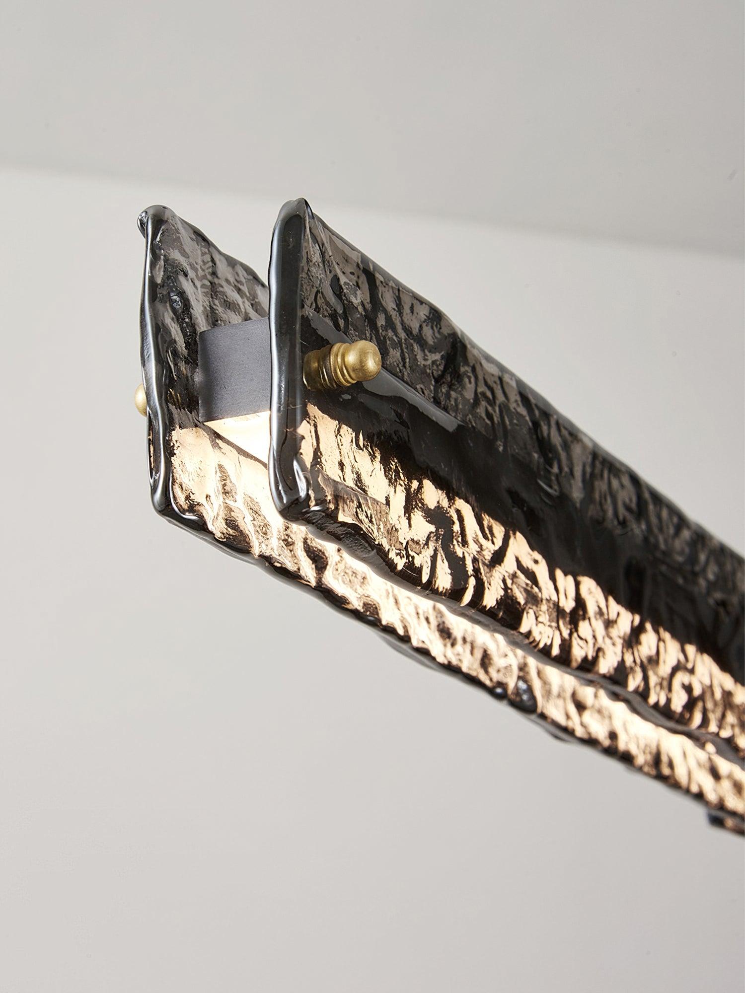 End close-up of two dark textured glass panels around a lit central body, with gold-tone fixing caps