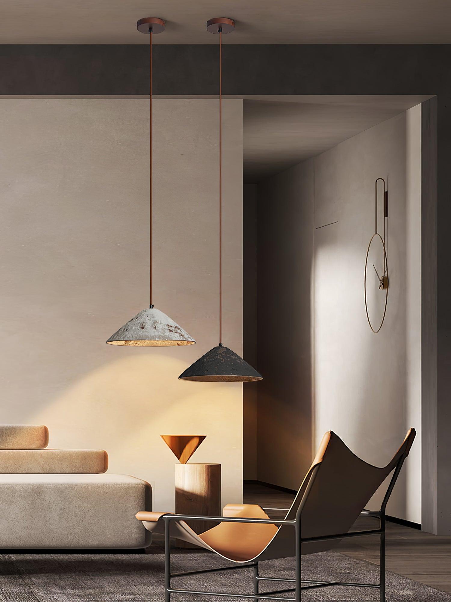 White and black cone pendants on separate long cords and brown canopies, above a lounge chair near a large wall clock
