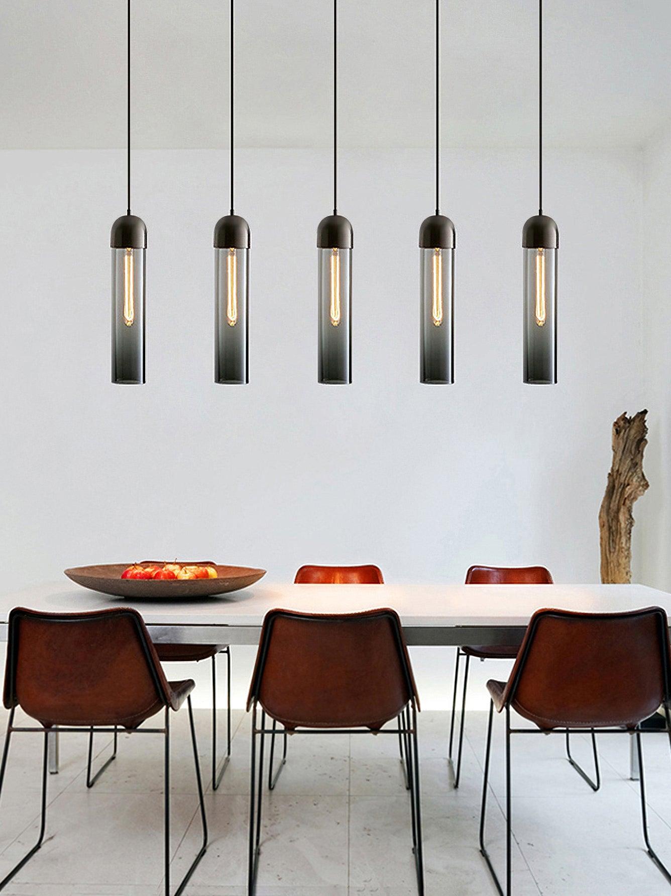 Five smoky glass cylinder pendant lights above a white dining table with reddish-brown chairs