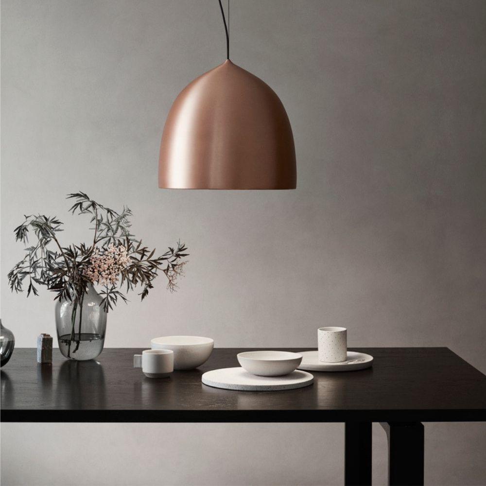 Copper-coloured shade above crockery and branches