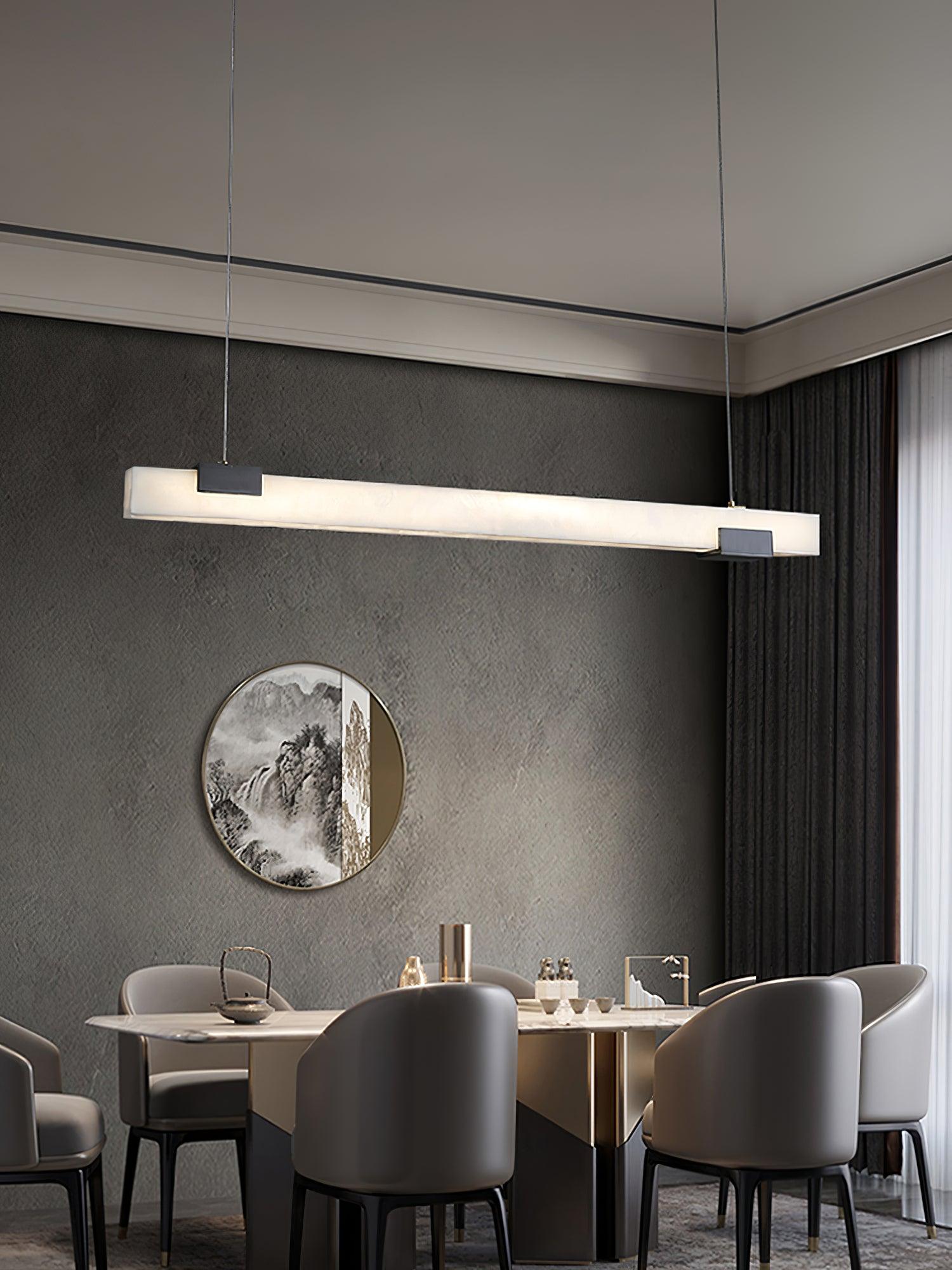 White linear pendant above a dining table with grey chairs, dark curtains and circular landscape artwork