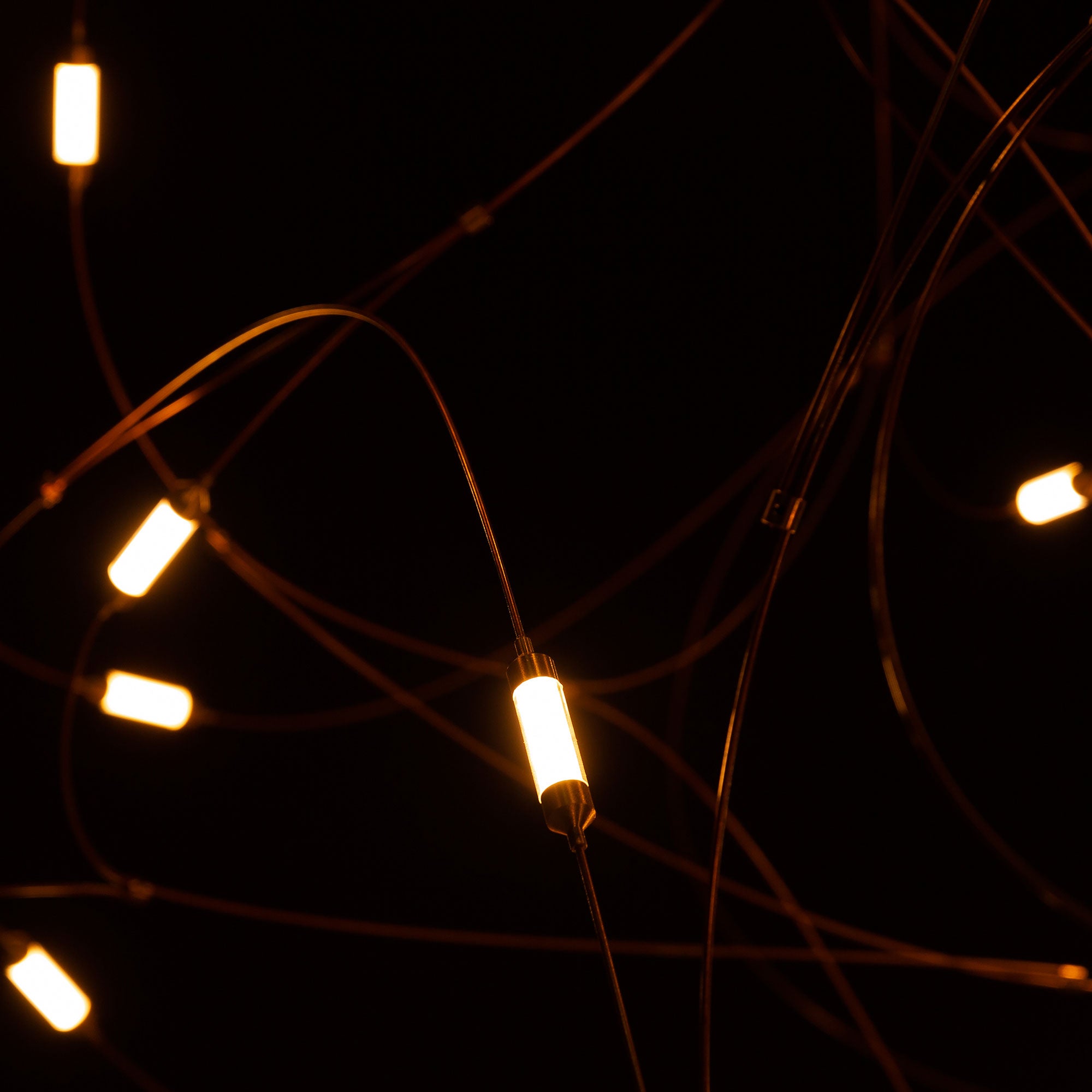Close crossing gold-tone wires and small glowing cylindrical light sections