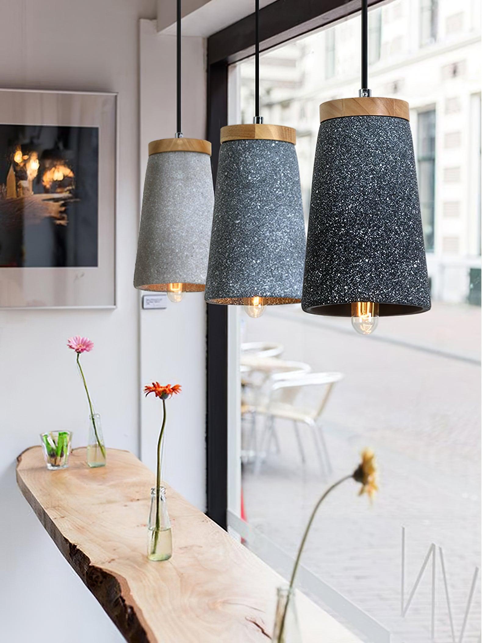 Three cement pendants above a wooden table near windows