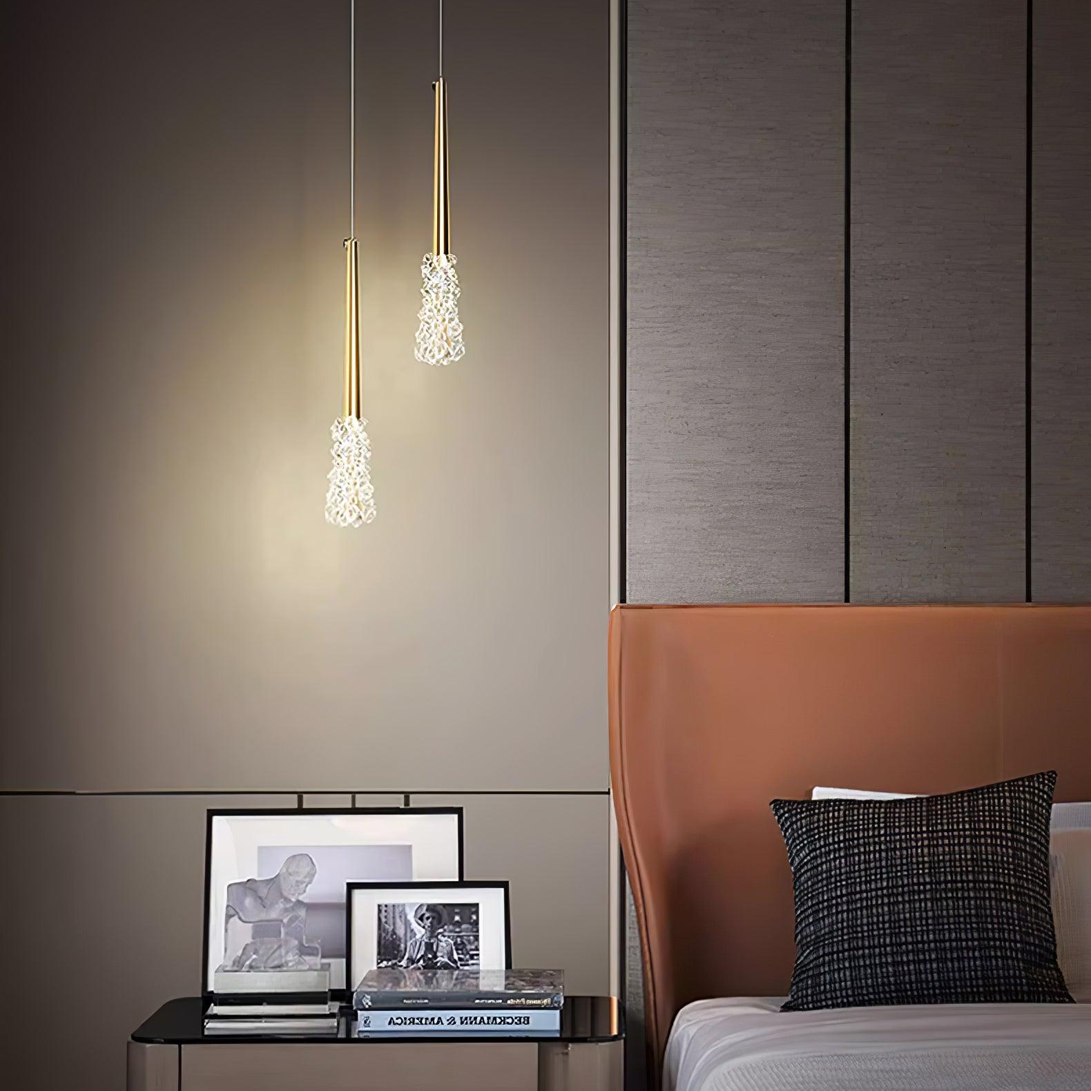 Two slim Gold pendants above a bedside cabinet