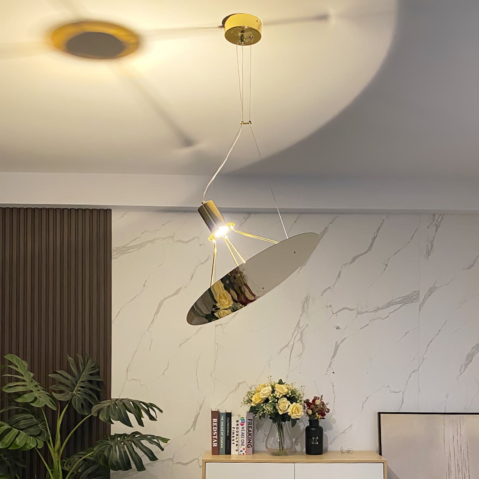 Gold reflector pendant casting light toward a ceiling