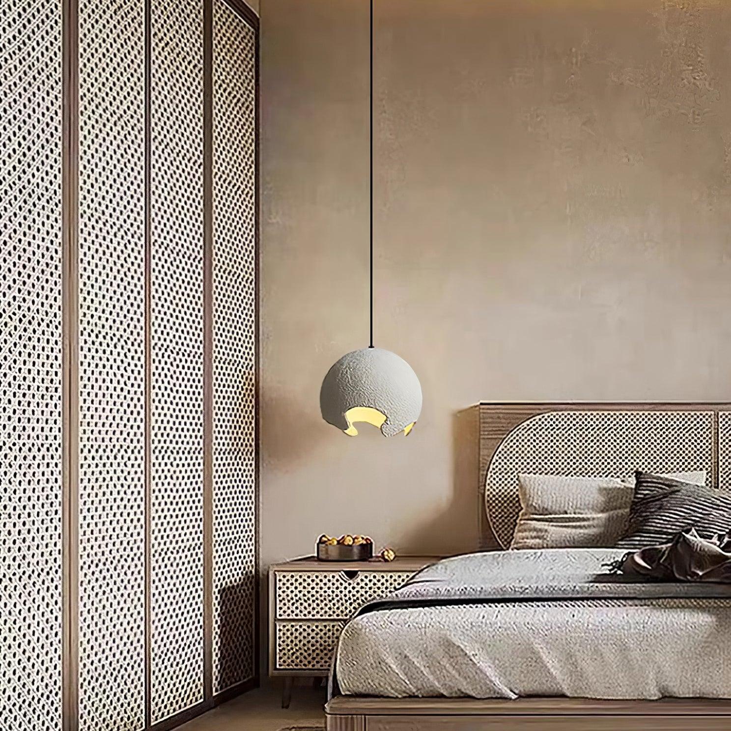 White globe pendant beside a bed and woven wall panels