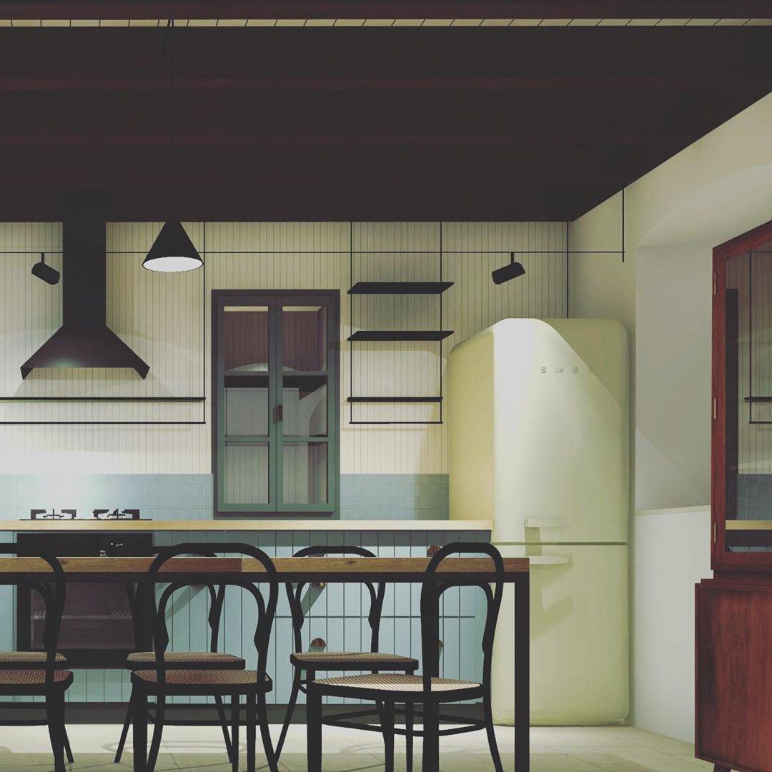 Black conical pendant over a wood dining table and dark chairs in a kitchen with a pale green fridge