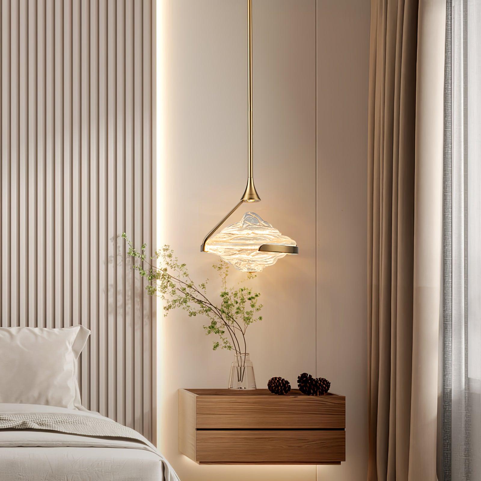 Gold-toned illuminated rippled-glass pendant above a floating wooden bedside drawer with branches and pine cones