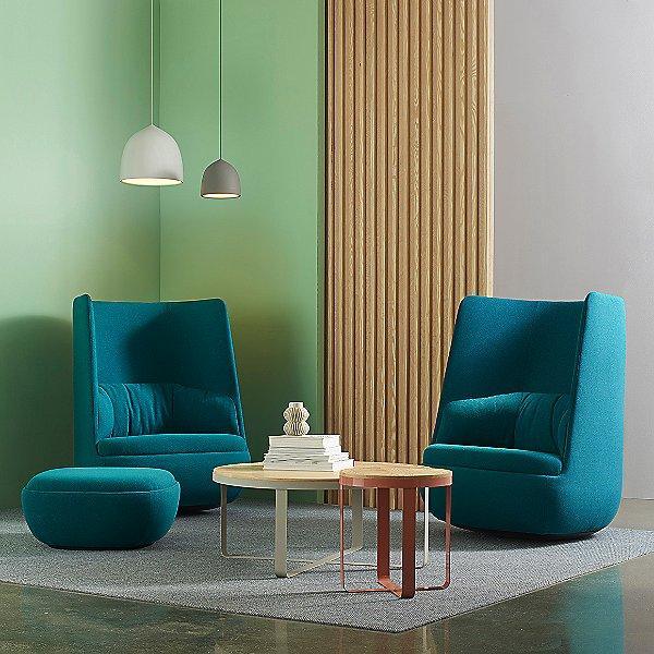 Two bell pendants above teal lounge chairs and small tables