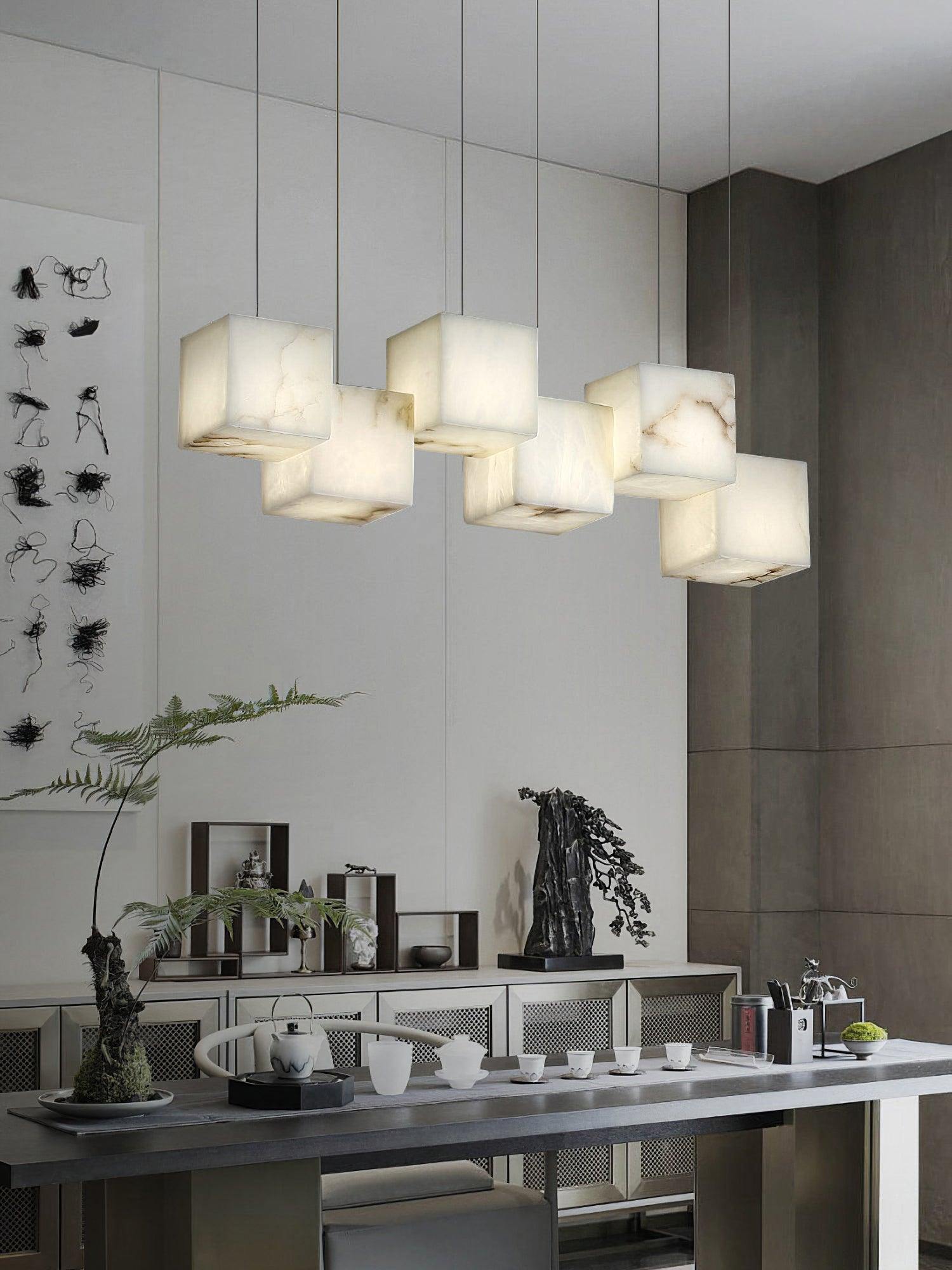 White cube pendant lights above a table set with teaware