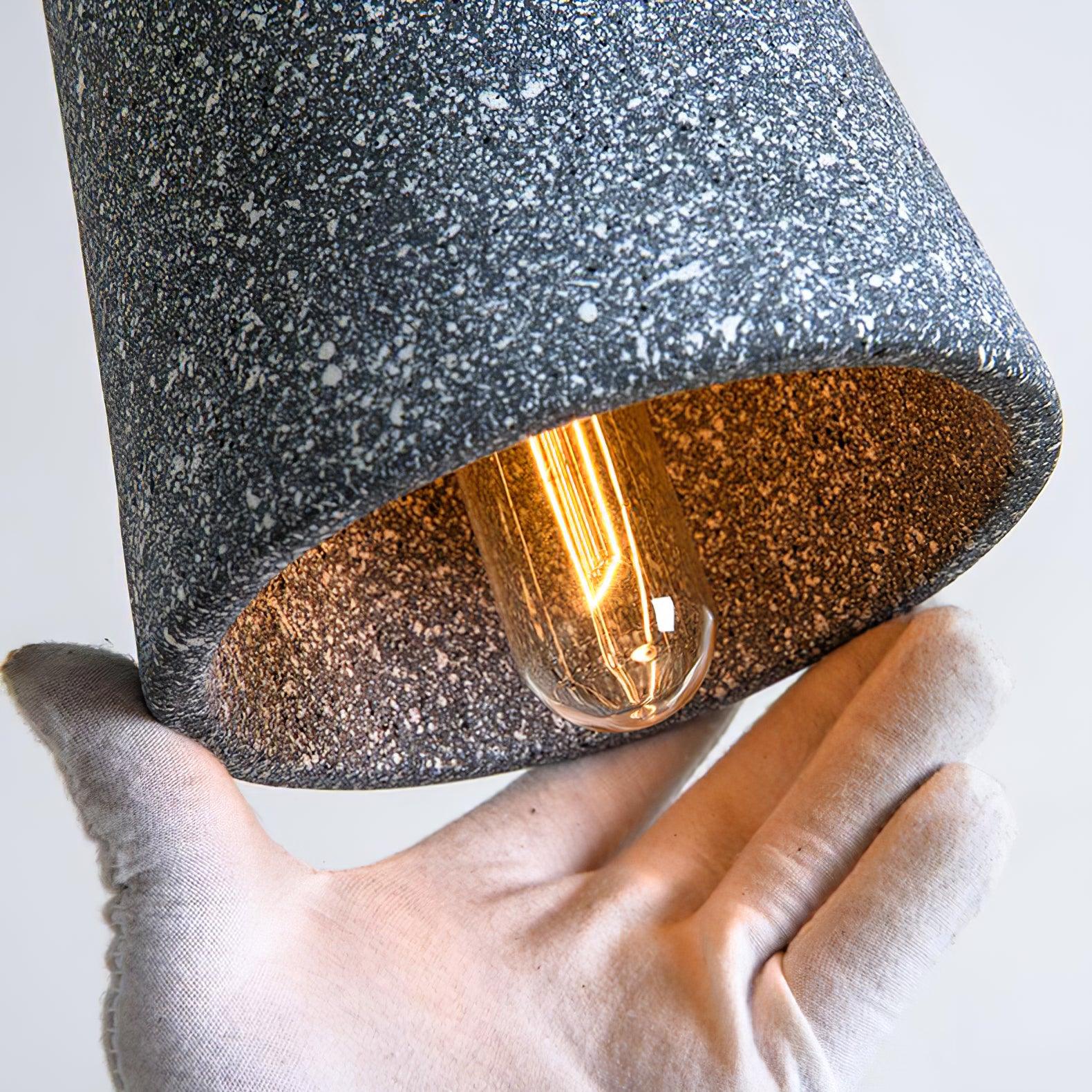 Hand holding a cement shade with thick speckled rim and visible bulb