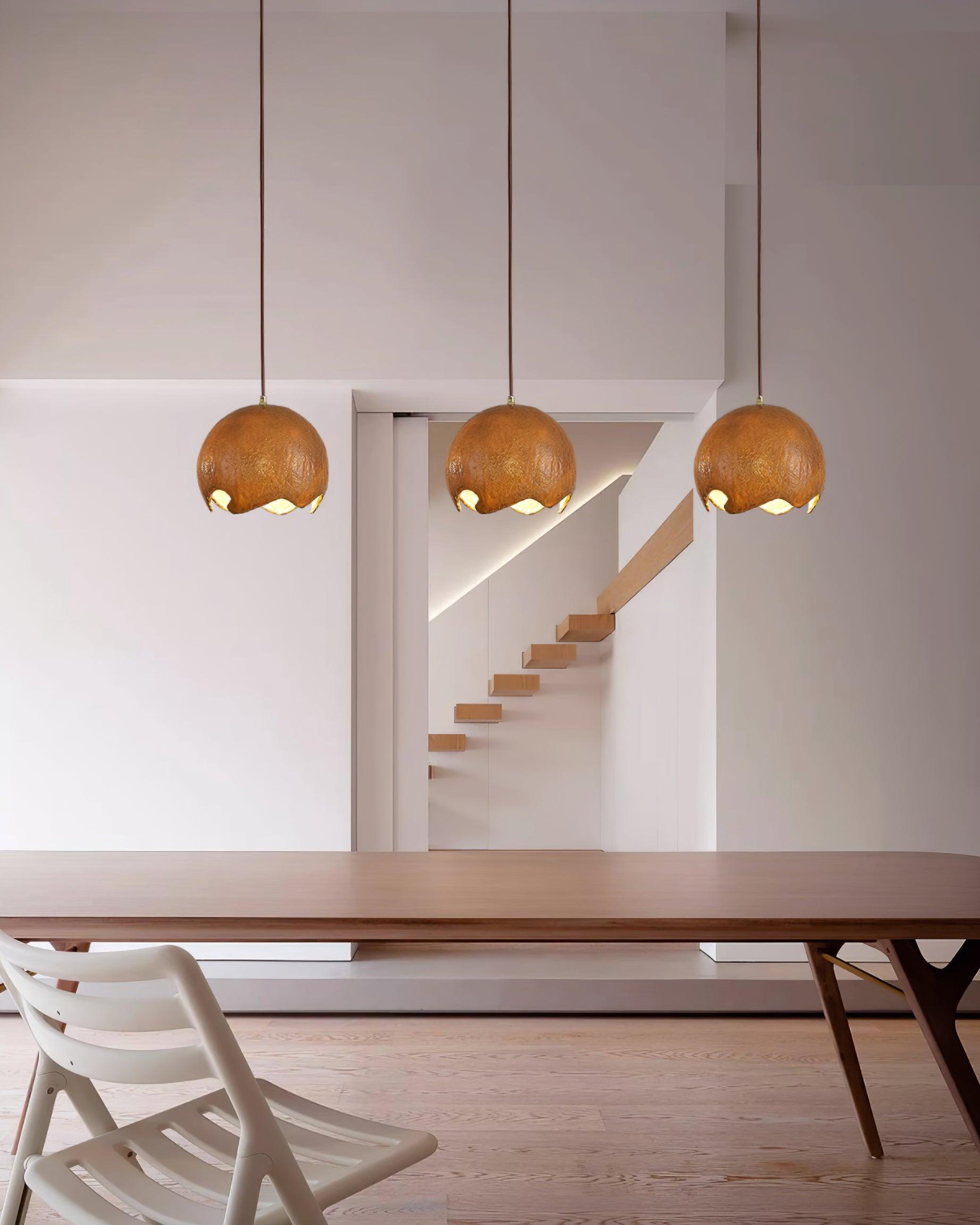 Three brown globe pendants above a long dining table