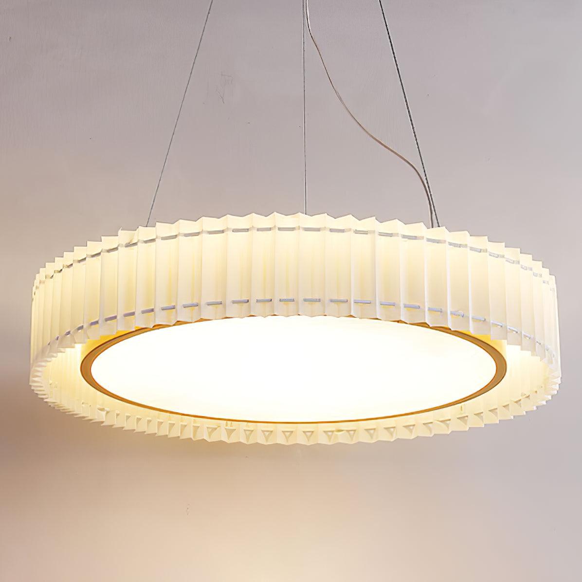 Low close view of the bright circular underside, gold-tone inner ring and surrounding cream pleated shade