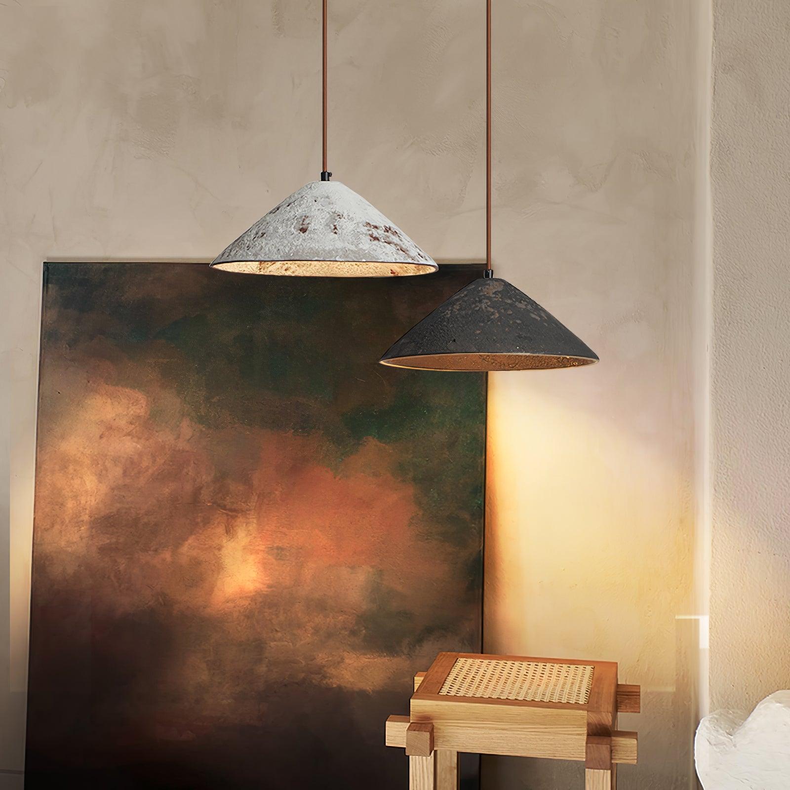 White and black textured cone pendants at different heights above a woven wooden stool, in front of a large abstract painting
