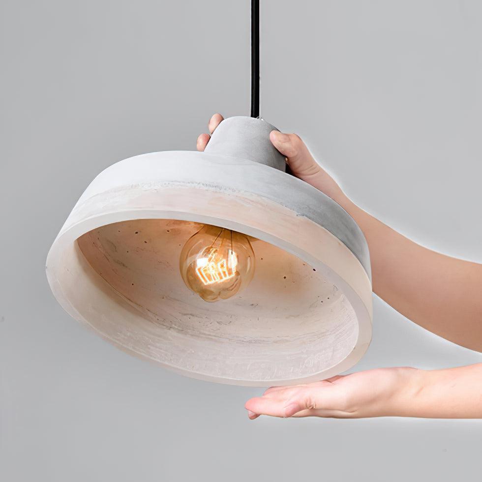 Hands holding a broad grey pendant shade to show the bulb and open underside