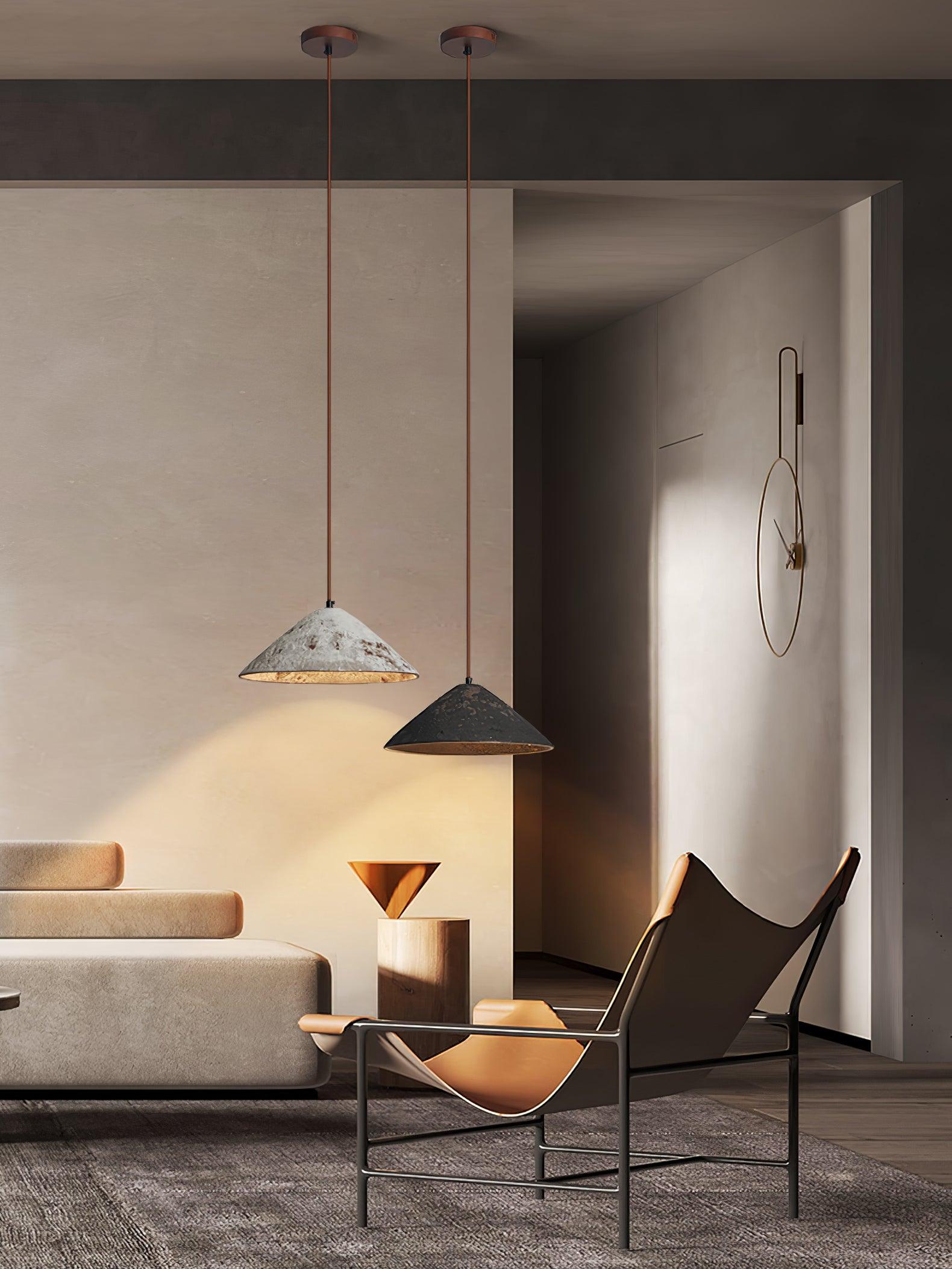 Two cone pendants from separate brown ceiling canopies over a lounge chair and sofa, beside a large wall clock