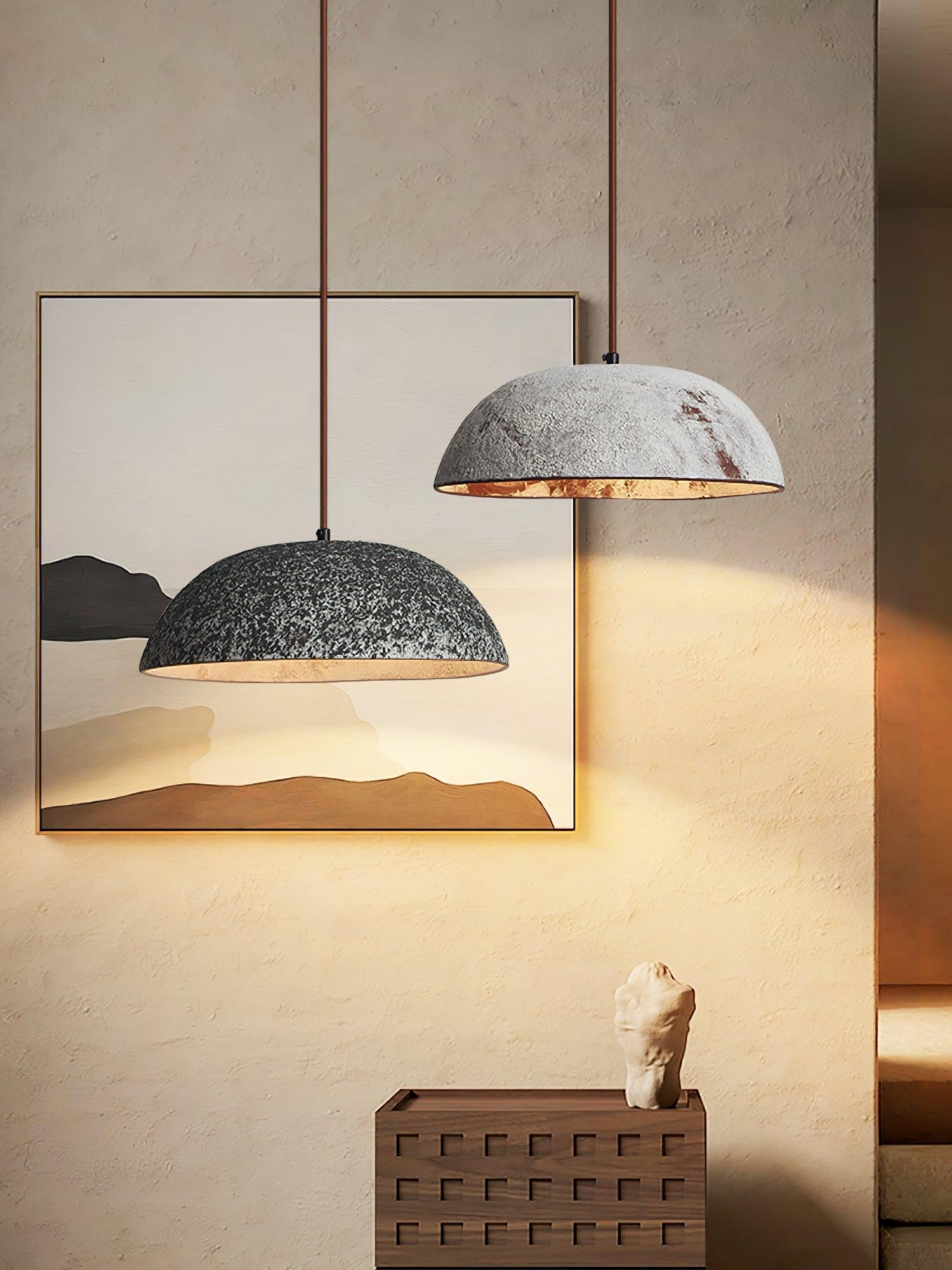 Dark and pale ceramic dome pendants at staggered heights in front of framed artwork