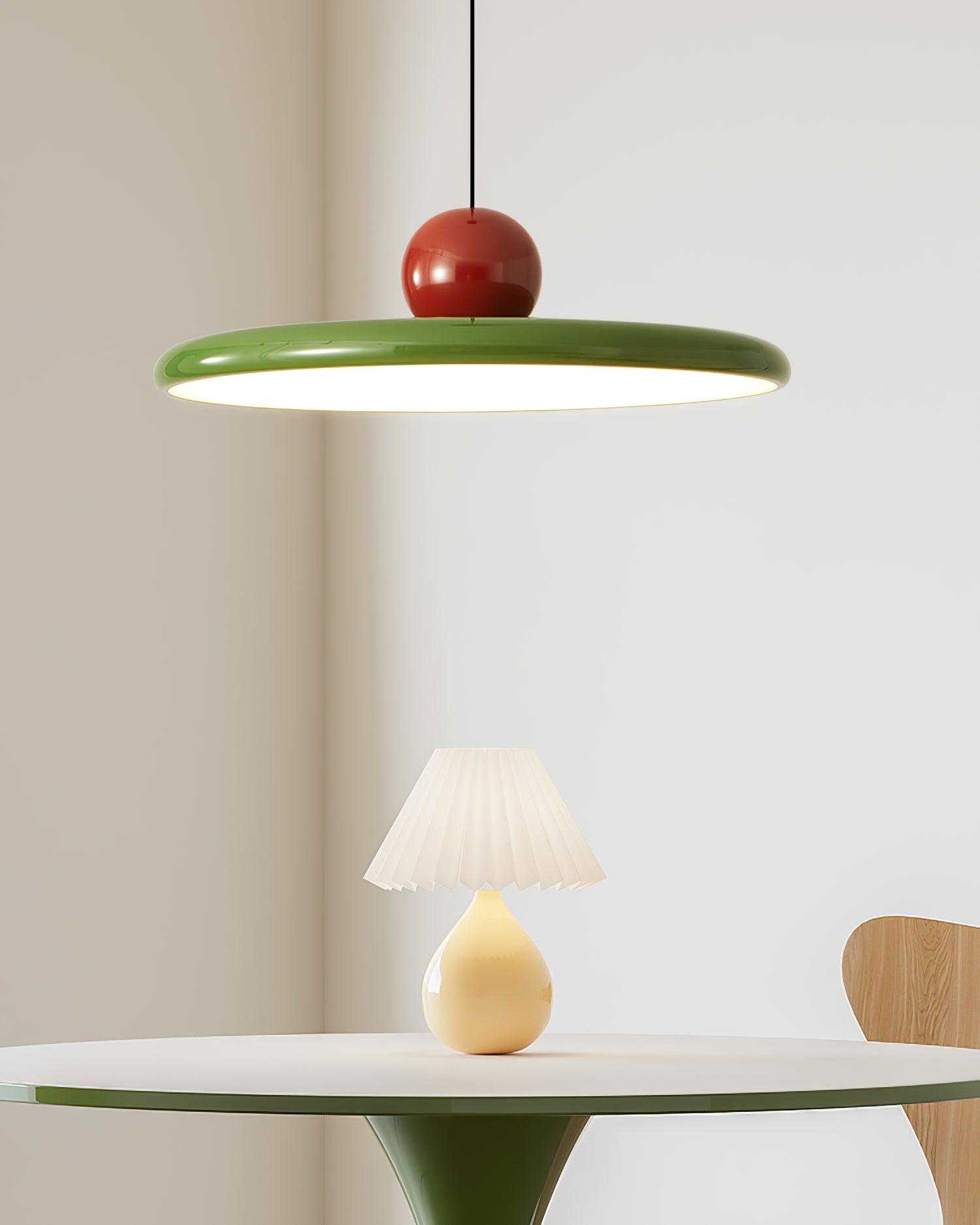 Green-rimmed Lola pendant above a table with a small lamp