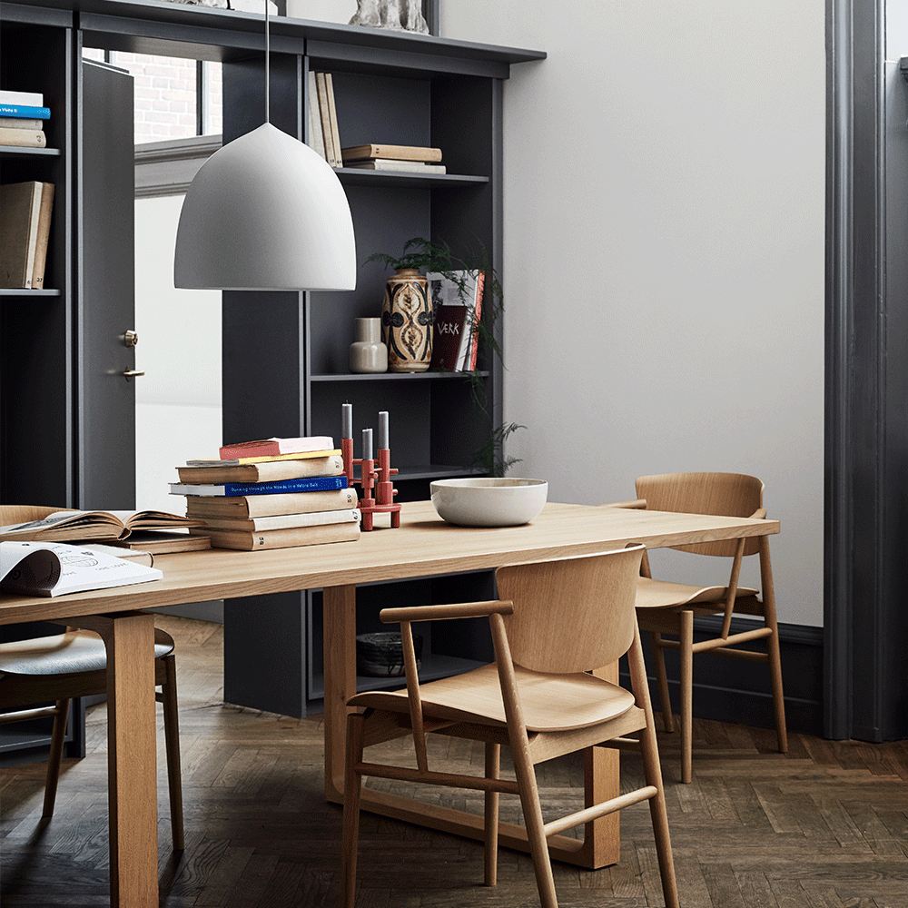 White bell pendant above a dining table with books