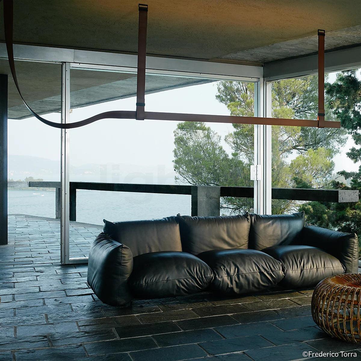 Dark strap pendant beside a large window and sofa