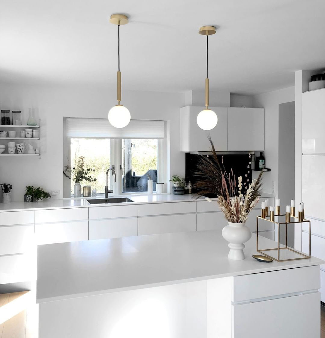 Two single white globe pendants above a kitchen island