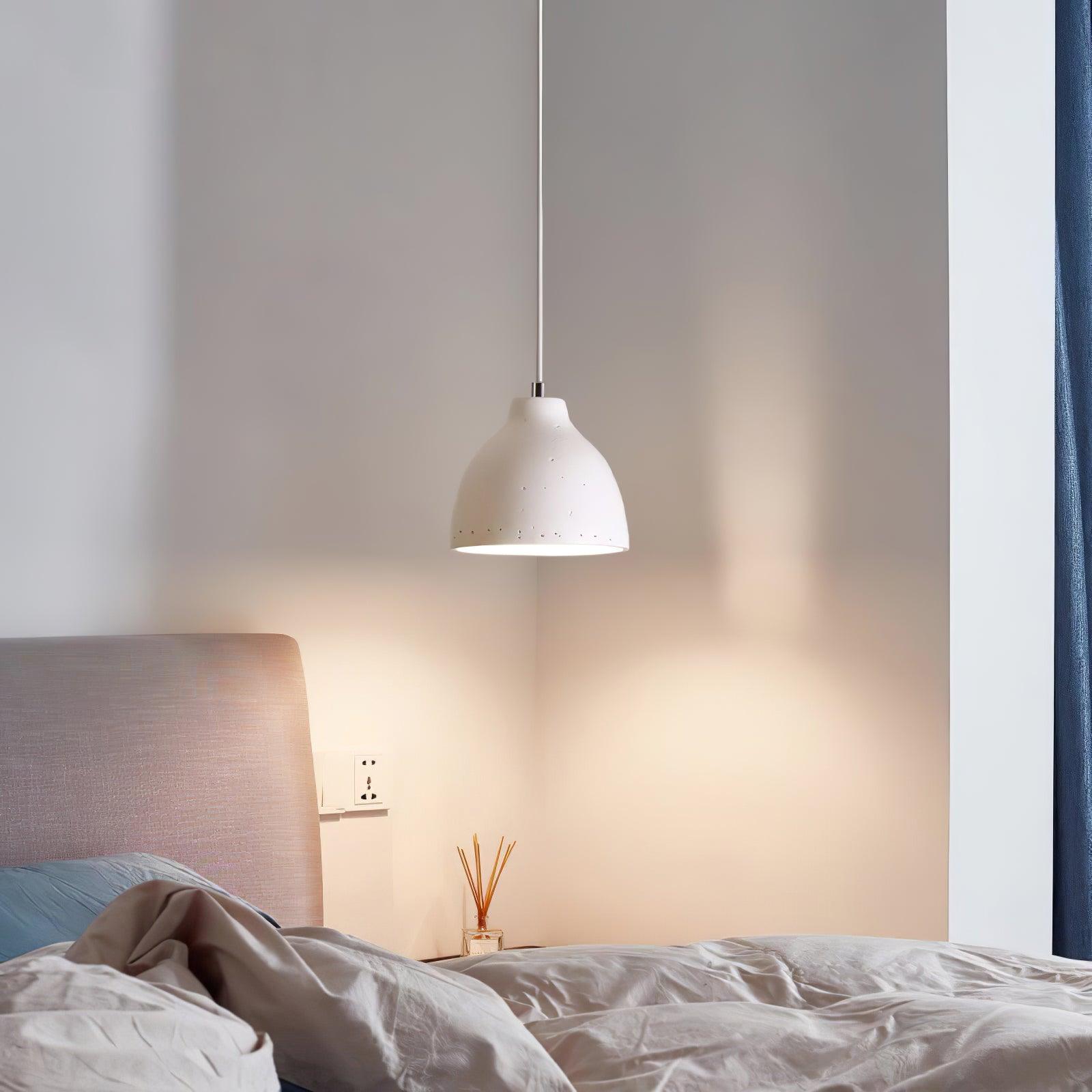 White bowl pendant beside a bed with a padded headboard