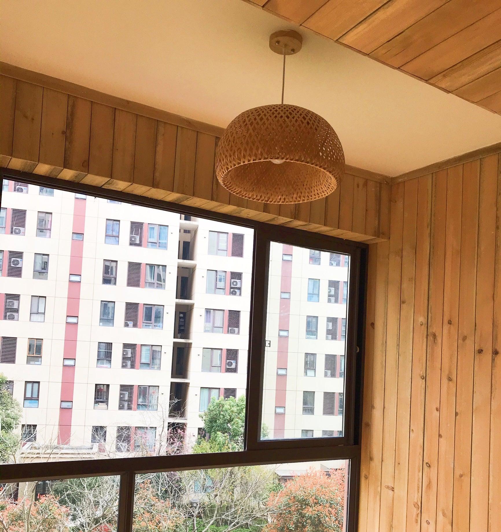 Unlit bamboo dome beside apartment-view windows with wood ceiling and wall cladding, pale canopy and suspension