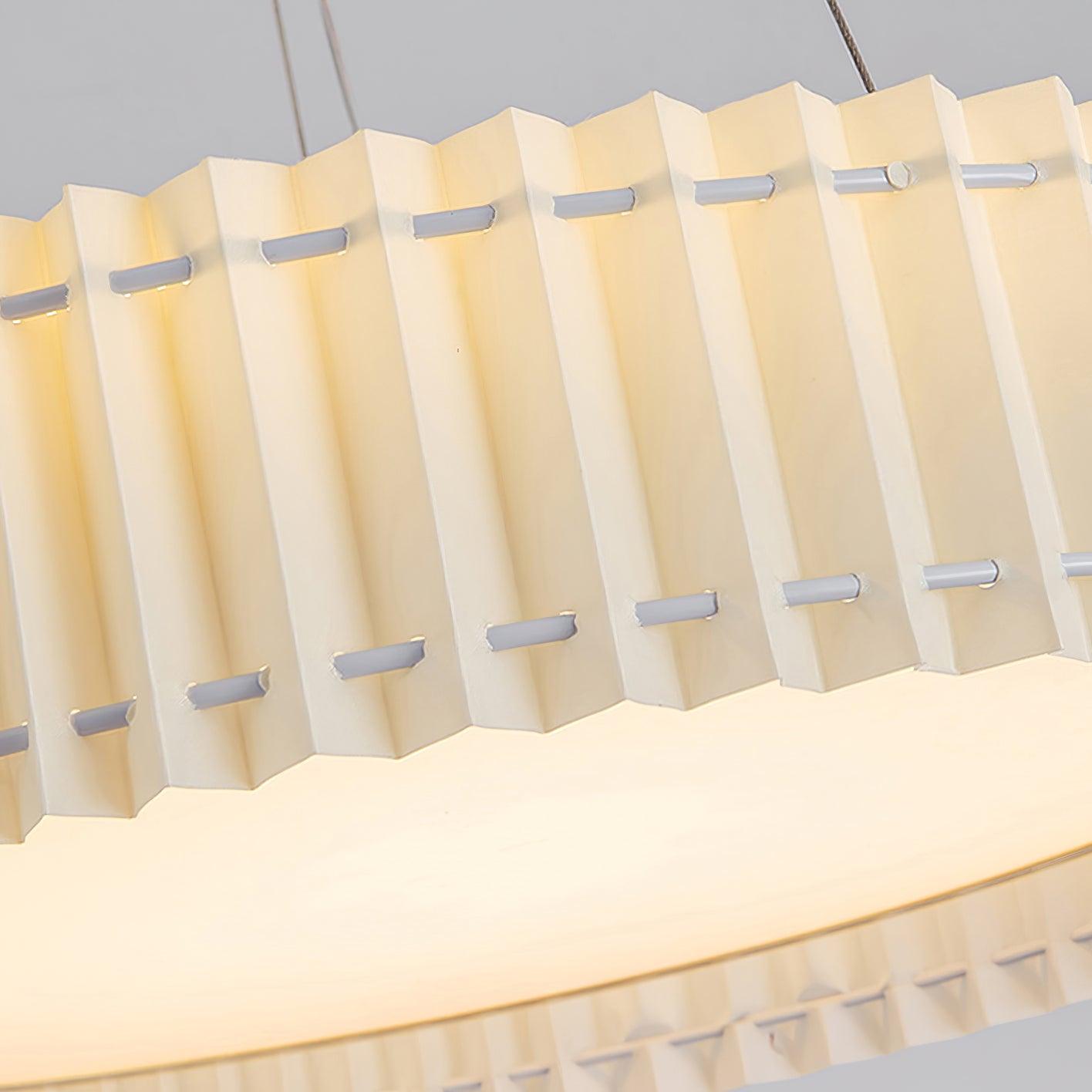 Close-up of cream pleats crossed by two rows of pale fastening details beside a gold-tone rim and lit lower panel