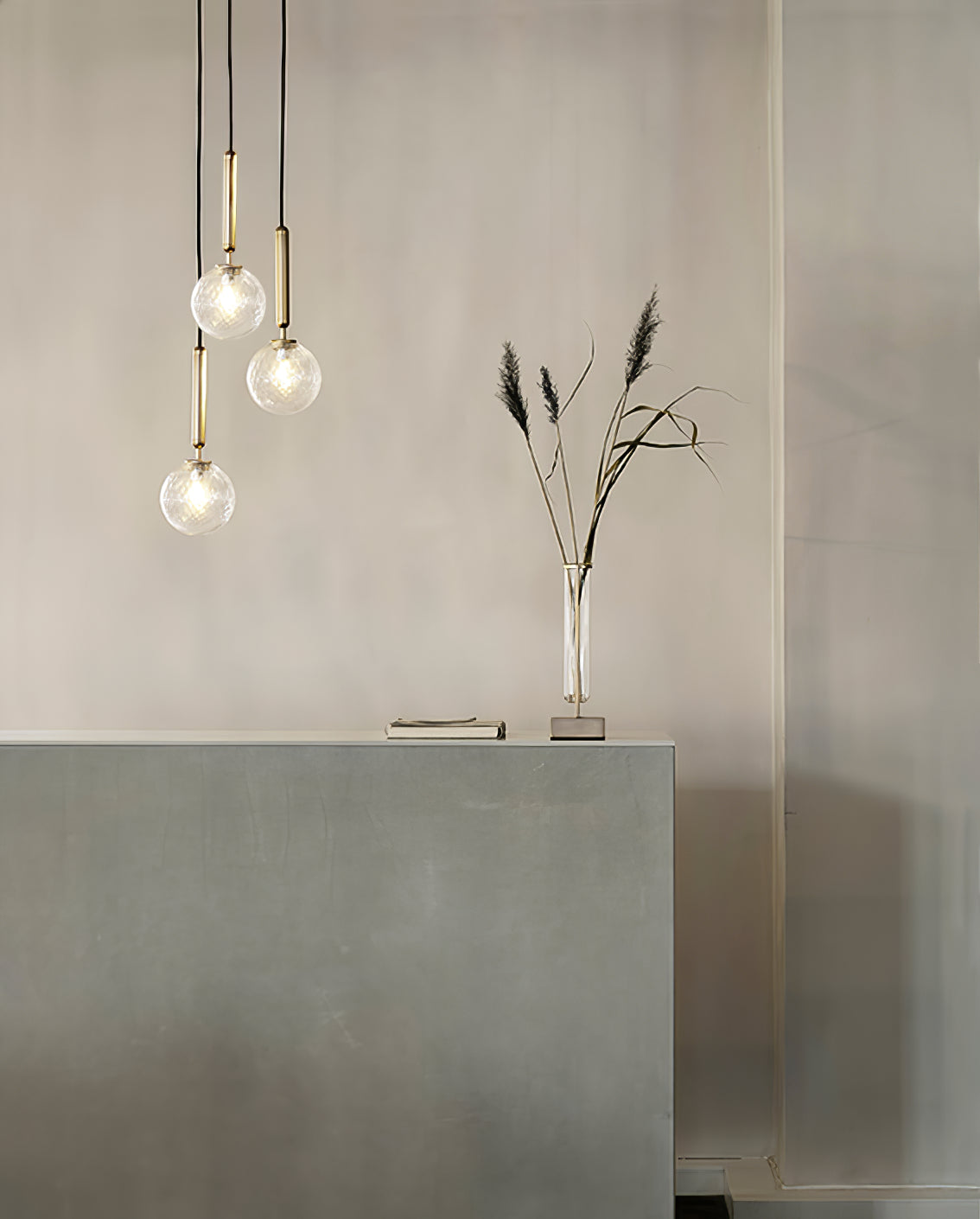 Clear globes at staggered heights beside a vase
