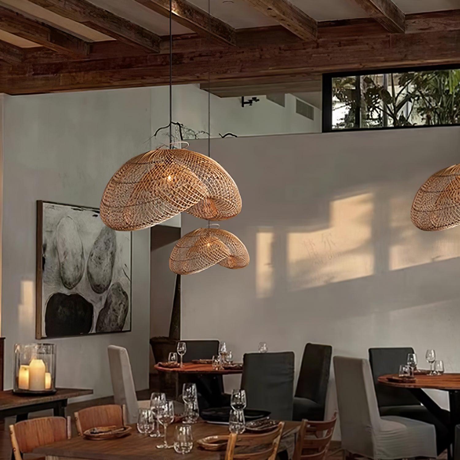 Separate woven wave pendants above dining tables with glassware, chairs and wall artwork under wooden beams